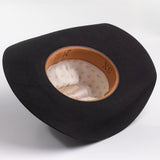 A black felt cowboy hat shown from a top-down angle, displaying its tan leather trim and cream-colored patterned interior lining
