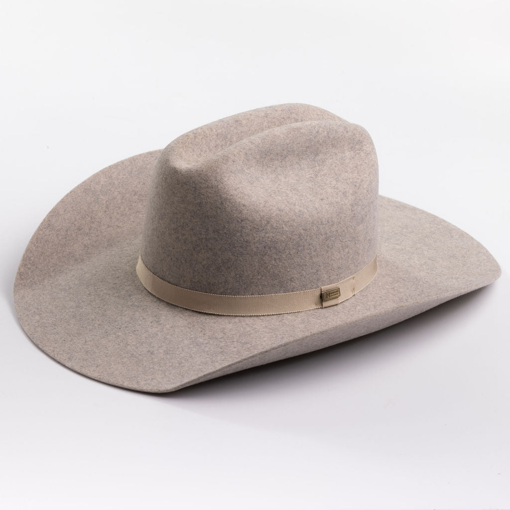 A light taupe felt cowboy hat with a matching felt crown and a beige fabric band around the middle, photographed on a clean light gray background