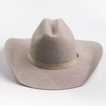 A light taupe felt cowboy hat with a matching felt crown and a beige fabric band around the middle, photographed on a clean light gray background