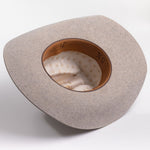 A light gray felt cowboy hat viewed from the inside, showing a tan leather inner band with black lettering and a cream patterned lining