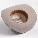 A light gray felt cowboy hat viewed from the inside, showing a tan leather inner band with black lettering and a cream patterned lining