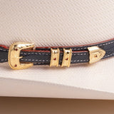 Close-up of a leather belt with gold buckle on an ivory colored hat