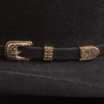 Close-up of a black belt with gold buckle