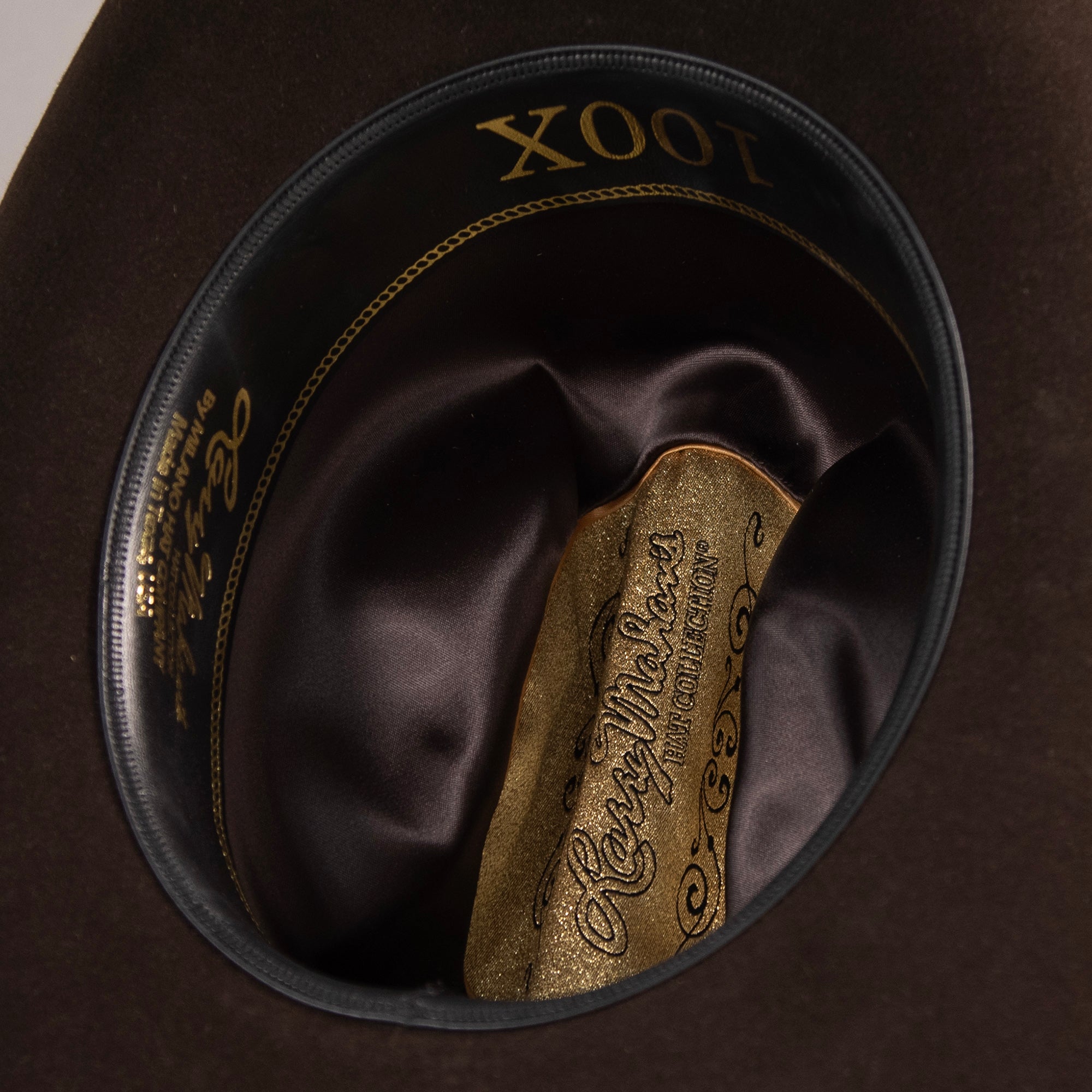 100X Independencia brown cowboy hat closeup of the underside with black interior, gold trim and lettering