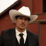 Man wearing a 1000X Imperial belly cowboy hat, a black jacket, vest, and tie, with a white shirt underneath