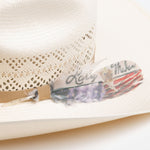 10X Tulsa closeup of a light brown band with a gold and black Larry Mahan pin and writing on a feather with a colored American flag along the bottom of the feather