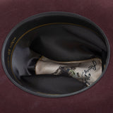 10X Jerarca black cherry cowboy hat closeup of the underside with black interior, gold trim and lettering
