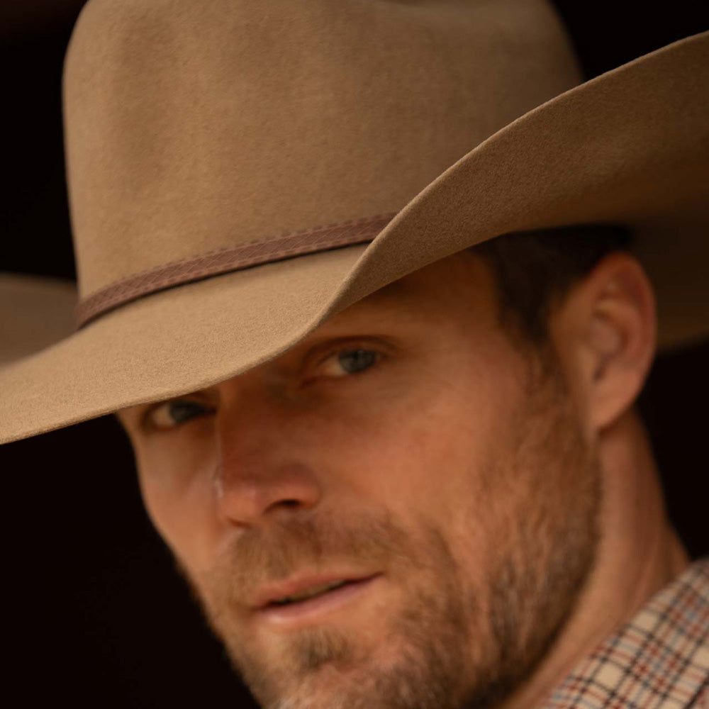 Closeup of a bearded man wearing a 3X Bandera fawn cowboy hat and red, blue, and tan plaid long sleeve shirt