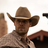 Bearded man wearing a 3X Bandera fawn cowboy hat and red, blue, and tan plaid long sleeve shirt