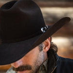 Man wearing a black cowboy hat with a blurred background