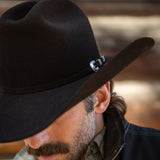Man wearing a black cowboy hat with a blurred background
