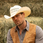Bearded man wearing a 10X Durant ivory cowboy hat and dark tan vest with blue collar shirt