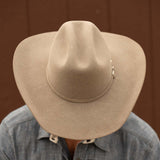 Bearded man wearing a 5X Fort Worth natural cowboy hat and blue long sleeve shirt looking downward to display the top of his hat