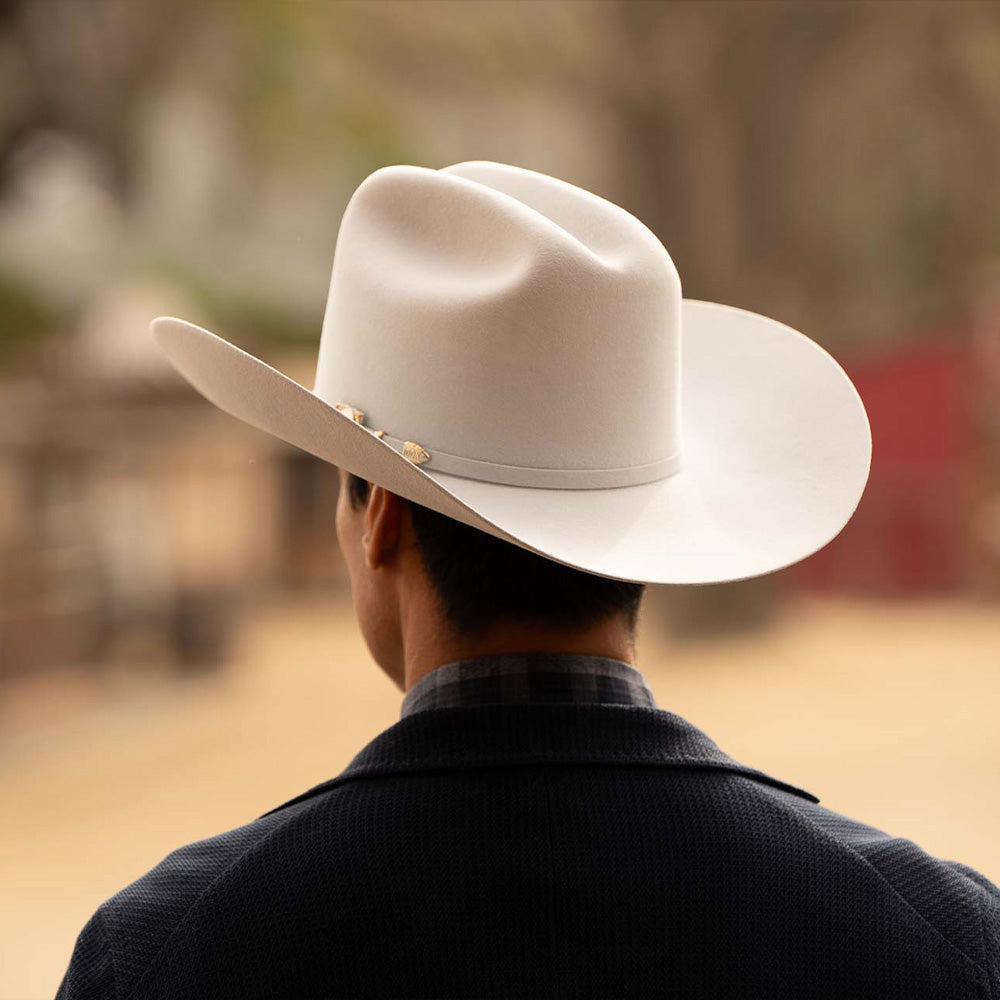 Man wearing a 100X Independencia belly cowboy hat with black jacket with him facing away to show the back of the hat and part of the silver buckle on the brim