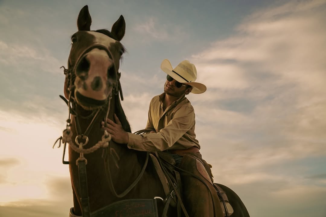 Man in cowboy hat sitting on a horse against a cloudy sky