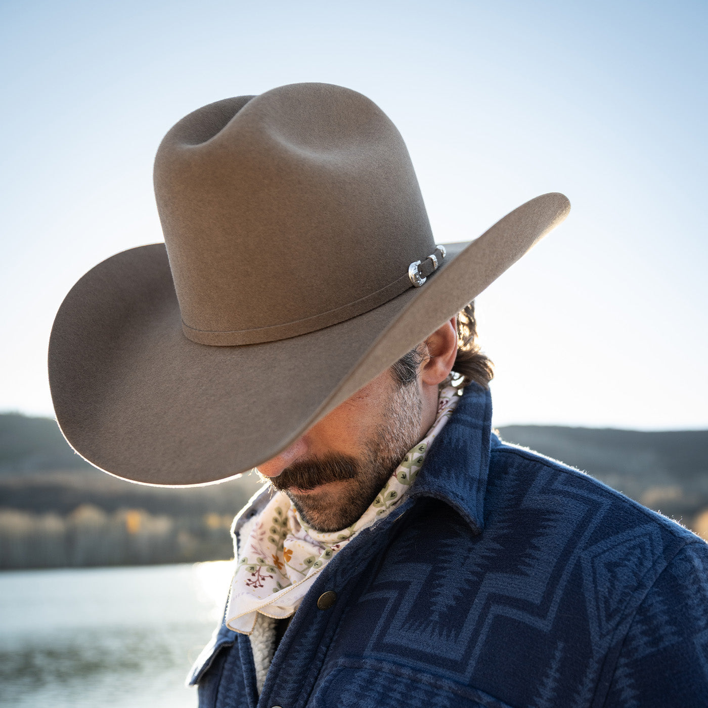Man wearing a cowboy hat with a scenic background