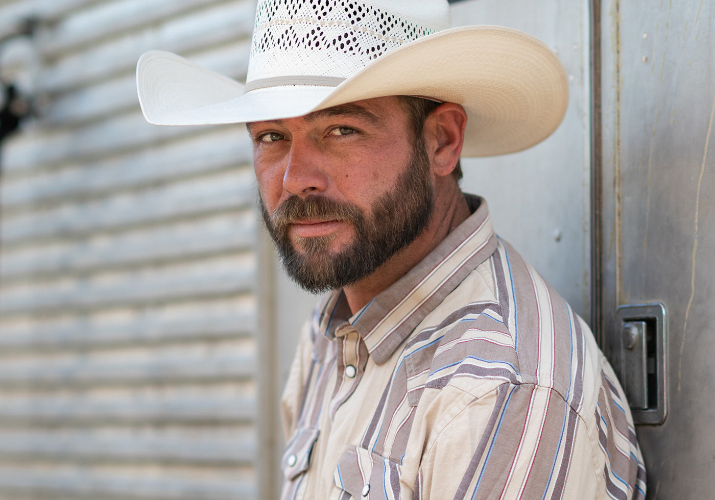 A white cowboy hat with a black band and white woven pattern band, resting on natural rocks outdoors