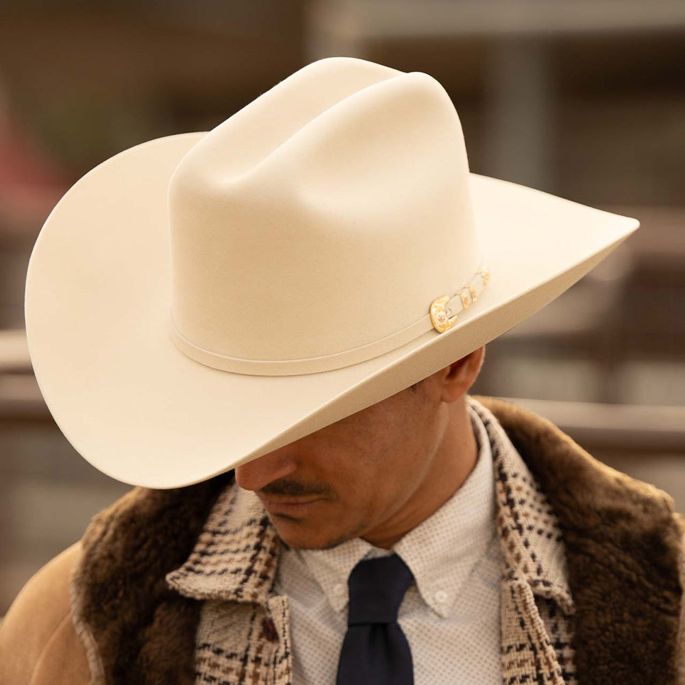 Man wearing a 500X Superior belly cowboy hat with a brown jacket with blue tie and white shirt looking down to the left
